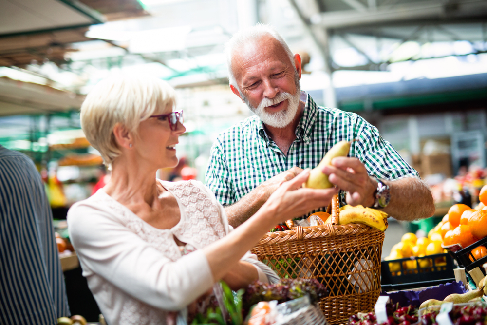 An elderly couple shopping fruits in a market